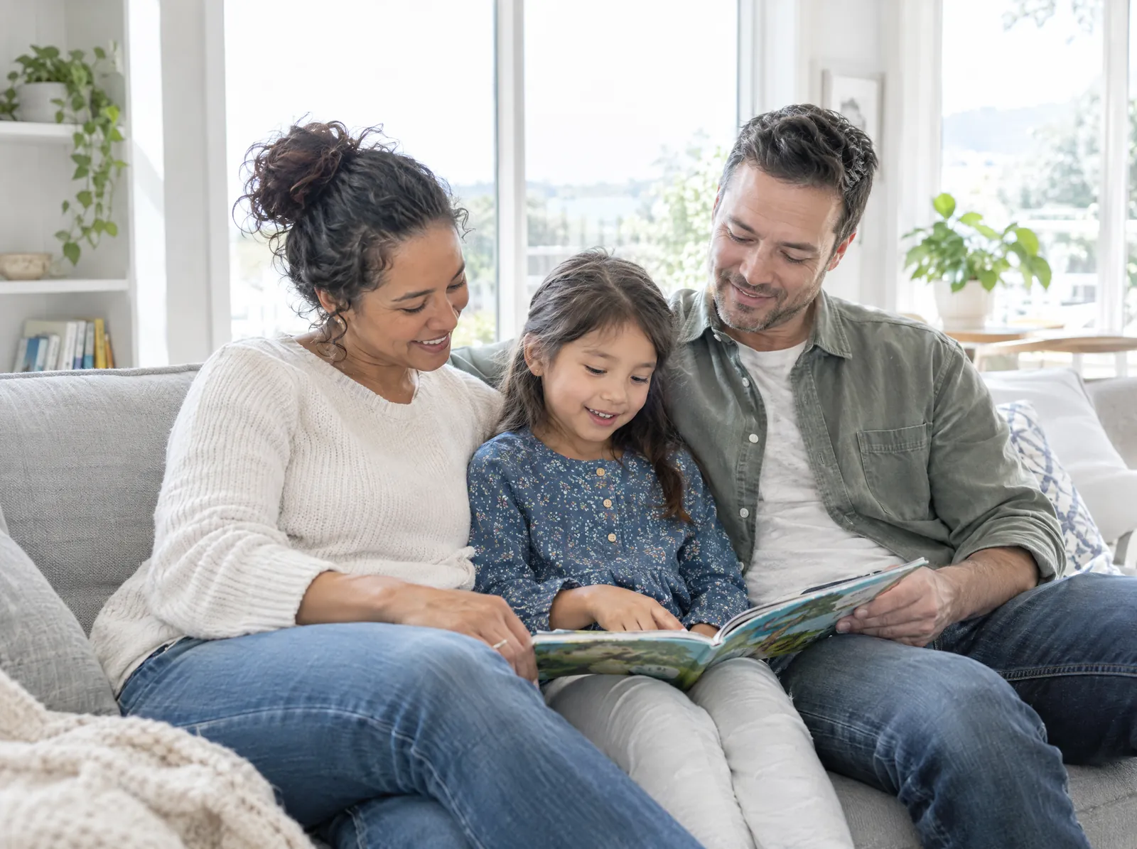 Family reading together on the sofa in a clean, bright living room
